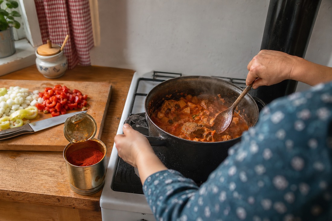 A cook stirring paprika stew in a Budapest kitchen during the market-to-table Hungarian cooking class
